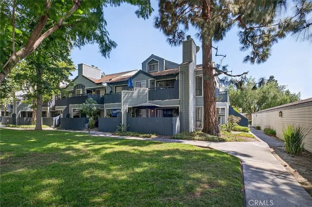 a view of a house with a small yard and a large tree
