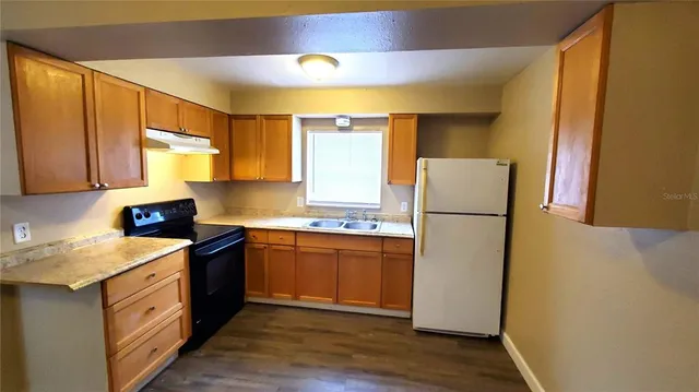 a kitchen with a refrigerator sink and wooden cabinets
