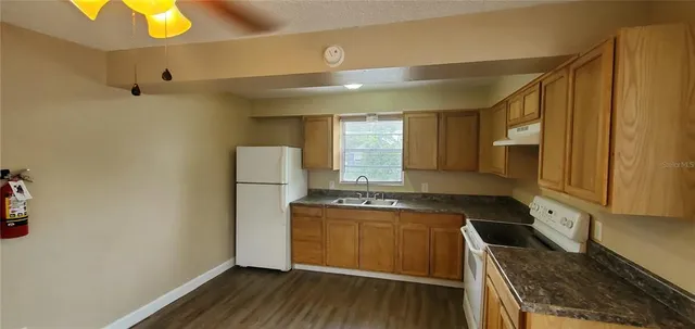 a kitchen with a sink a stove cabinets and wooden floor