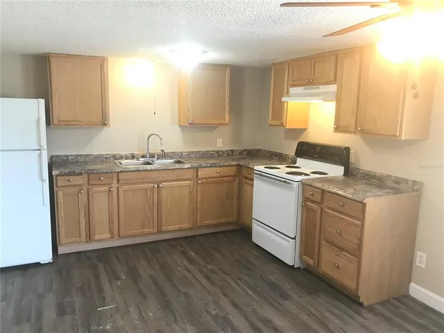 a kitchen with a sink white cabinets and white appliances
