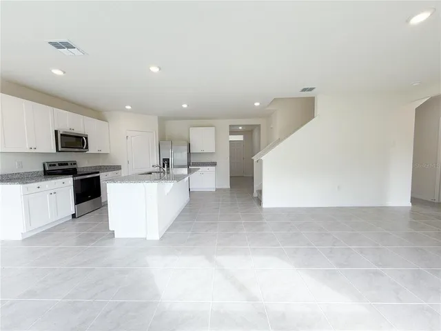 a large kitchen with stainless steel appliances kitchen island granite countertop a sink and white cabinets