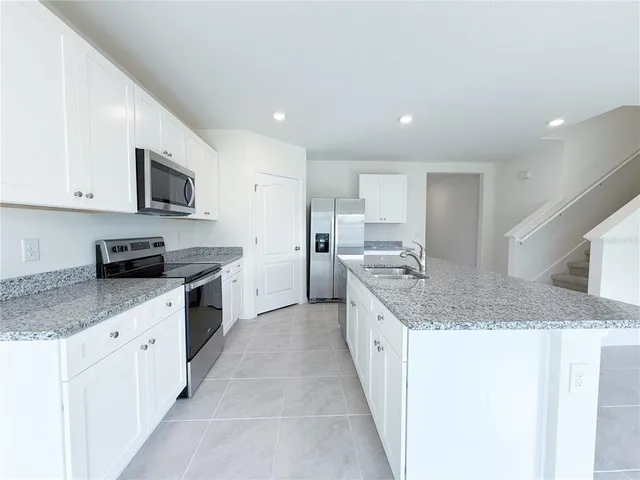 a kitchen with granite countertop a sink and a white wooden cabinets