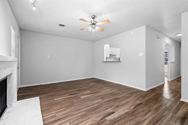 a view of an empty room with wooden floor and a ceiling fan