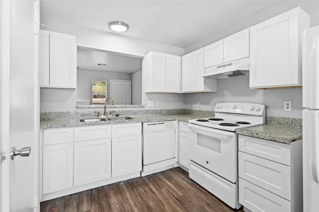 a kitchen with granite countertop white cabinets and white appliances