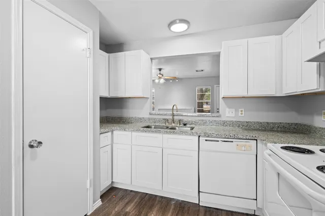 a kitchen with granite countertop white cabinets white appliances and a sink