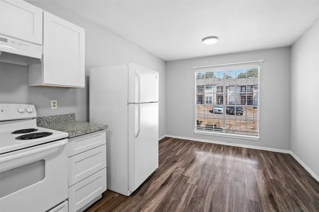 a kitchen with white cabinets and wooden floor