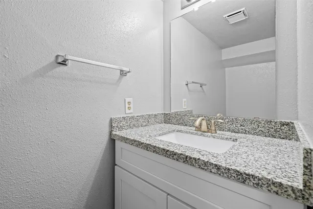 a bathroom with a granite countertop sink and mirror