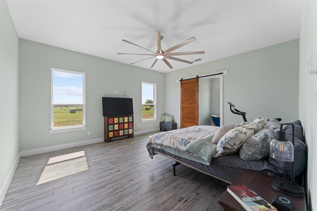 4411 Fm 751 Wills Point Wills Point, TX 75169 - Photo 19 of 40 Spacious room featuring wood-finish flooring, two windows, and a large ceiling fan with integrated lighting