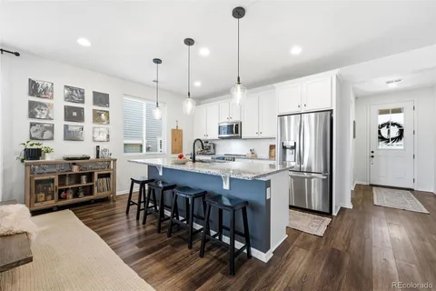 a large kitchen with kitchen island a large island a stove a refrigerator a counter space and wooden floor