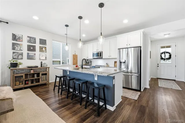 a large kitchen with kitchen island a large island a stove a refrigerator a counter space and wooden floor