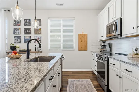 a kitchen with stainless steel appliances granite countertop a sink stove and cabinets