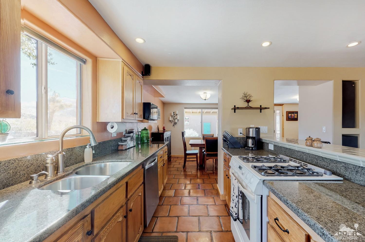 63443 Quail Springs Road Joshua Tree, CA 92252 - Photo 7 of 17 a kitchen with stainless steel appliances granite countertop a sink stove and cabinets