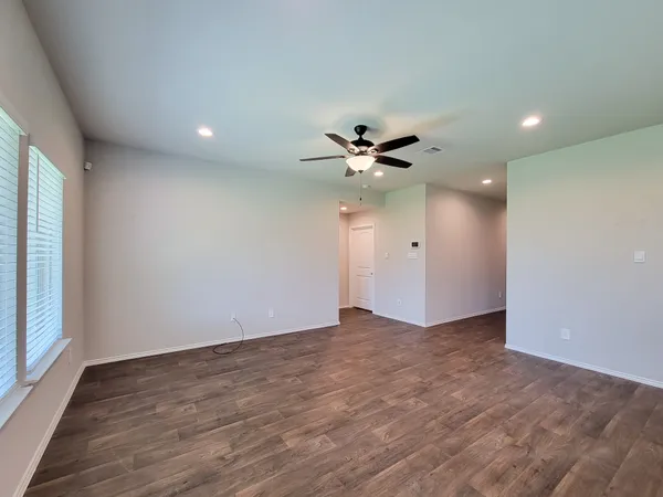 an empty room with wooden floor and windows