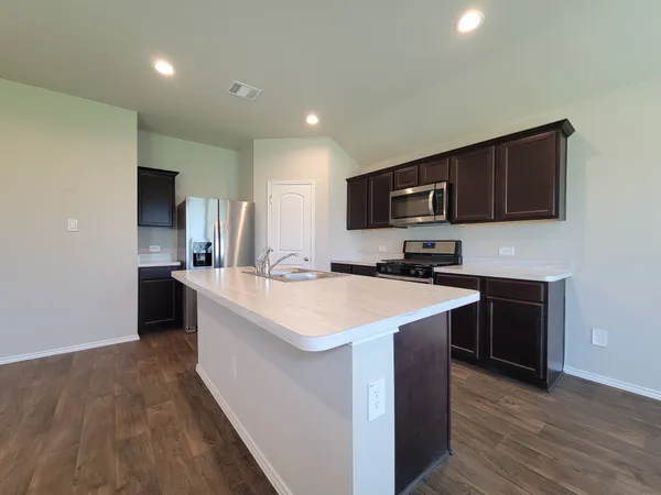 a view of kitchen island a sink wooden floor and cabinetry