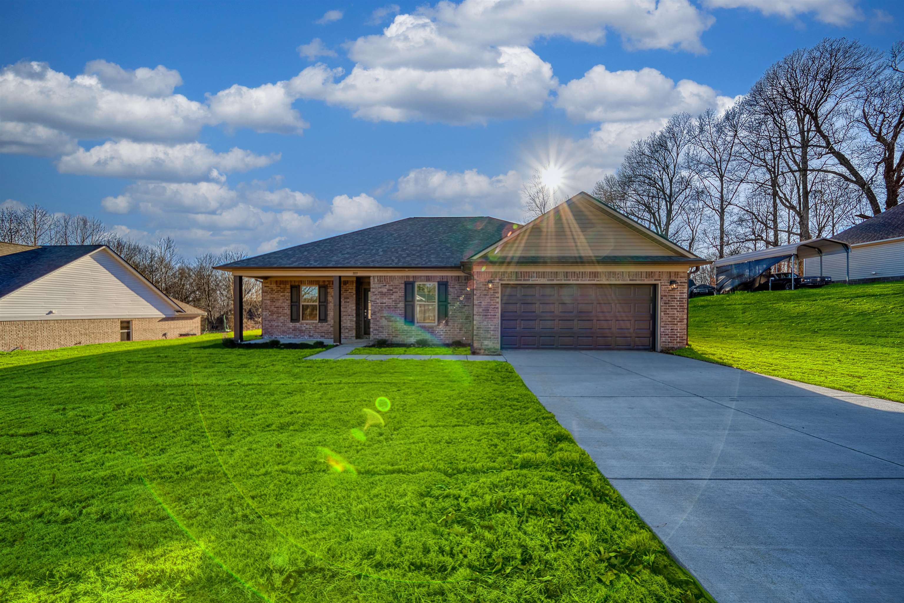 Single story home with a front yard, driveway, and brick siding