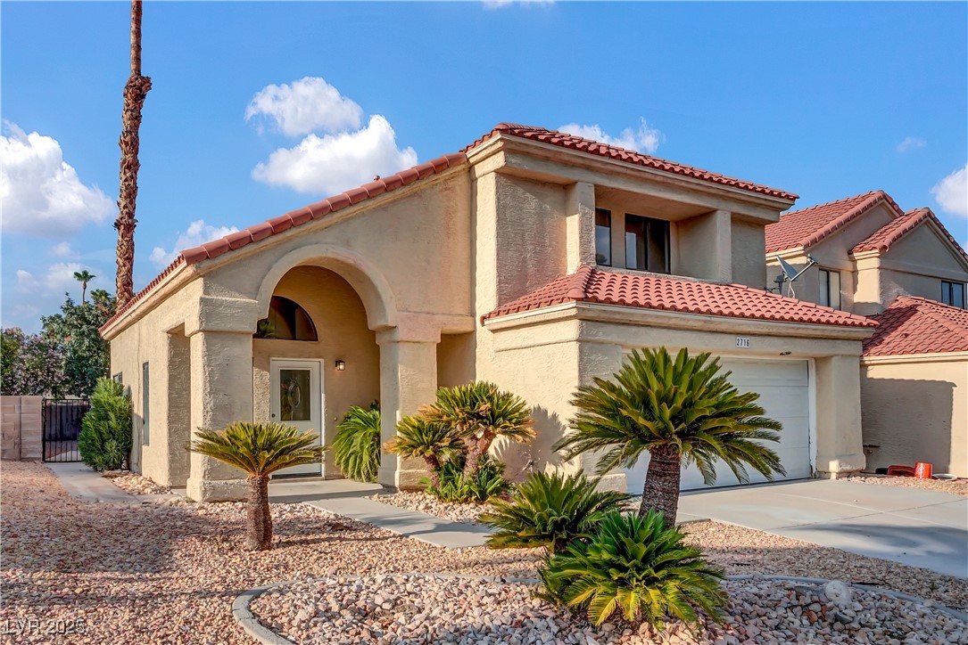 Mediterranean / spanish-style house featuring a tile roof, stucco siding, and driveway