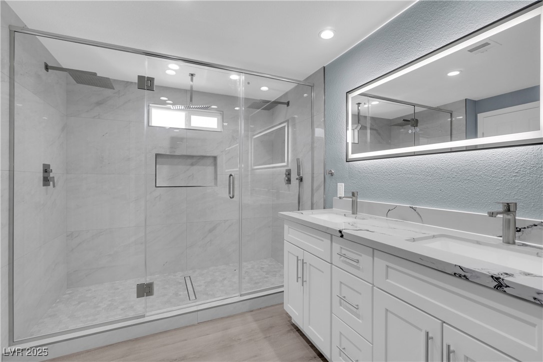 2716 Knightsbridge Road Henderson, NV 89074 - Photo 11 of 27 Full bathroom featuring a textured wall, a marble finish shower, double vanity, light wood-style flooring, and recessed lighting