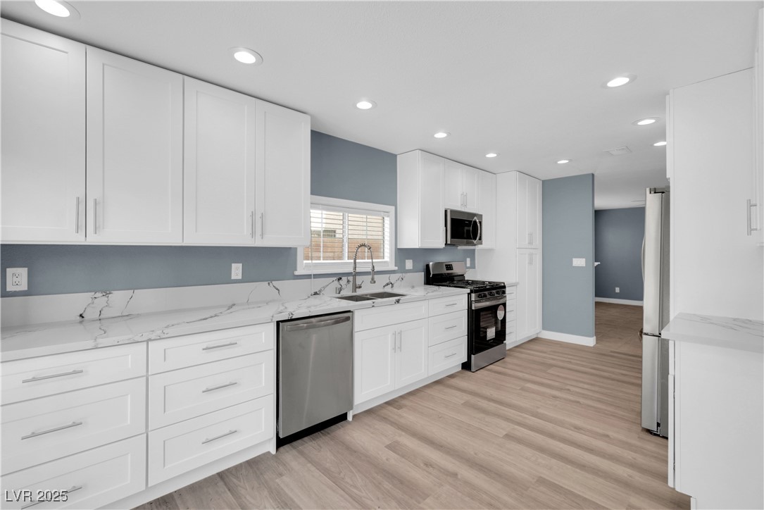 2716 Knightsbridge Road Henderson, NV 89074 - Photo 13 of 27 Kitchen featuring appliances with stainless steel finishes, white cabinets, light stone counters, recessed lighting, and light wood-style floors