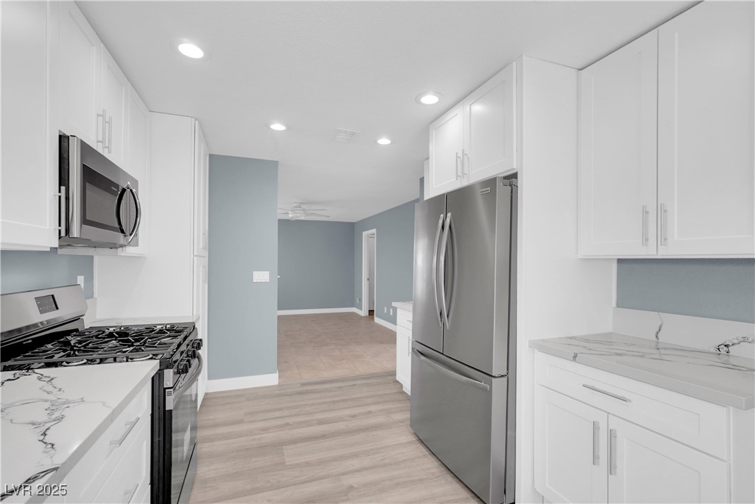 2716 Knightsbridge Road Henderson, NV 89074 - Photo 14 of 27 Kitchen featuring appliances with stainless steel finishes, white cabinetry, light stone counters, recessed lighting, and light wood-style floors
