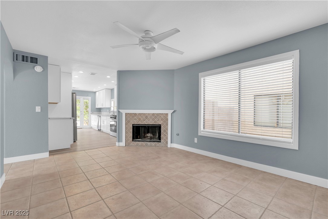2716 Knightsbridge Road Henderson, NV 89074 - Photo 15 of 27 Unfurnished living room with a tile fireplace, light tile patterned floors, and a ceiling fan