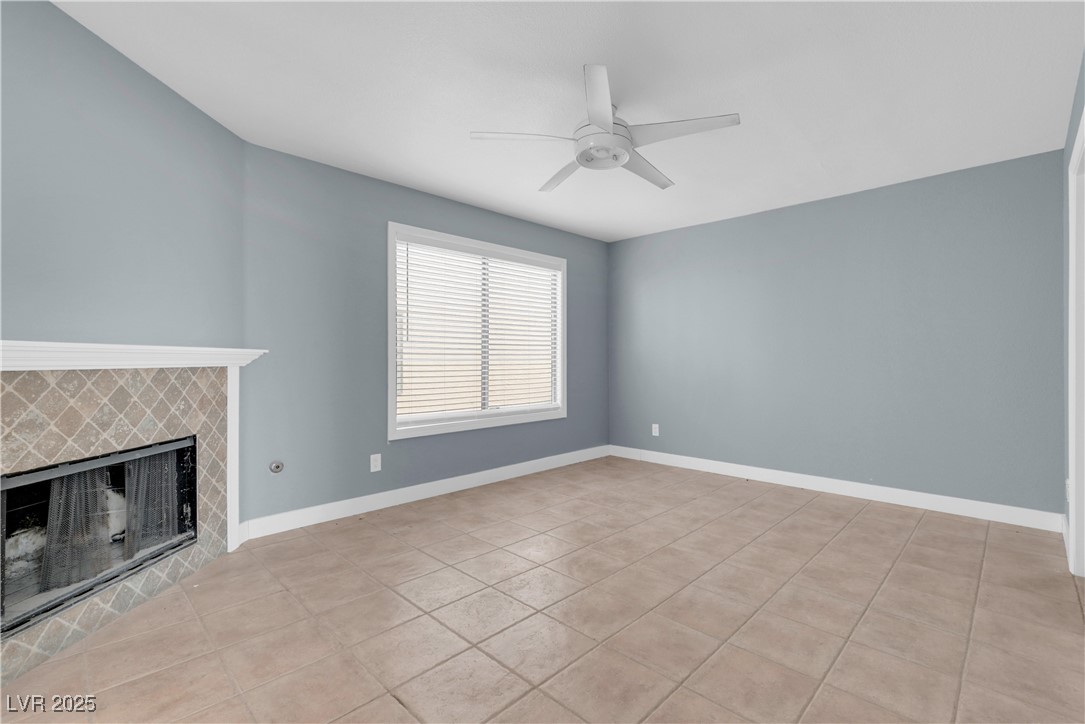 2716 Knightsbridge Road Henderson, NV 89074 - Photo 17 of 27 Unfurnished living room featuring light tile patterned floors, a tiled fireplace, and a ceiling fan