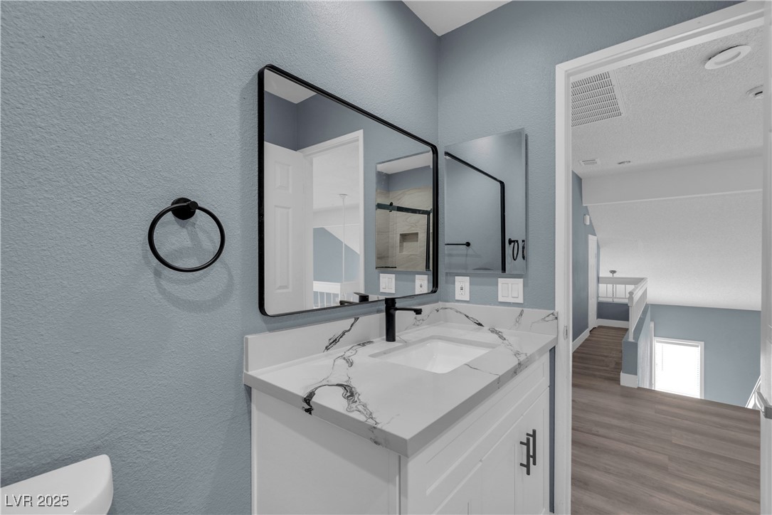 2716 Knightsbridge Road Henderson, NV 89074 - Photo 19 of 27 Bathroom with a textured wall, vanity, wood finished floors, and a shower