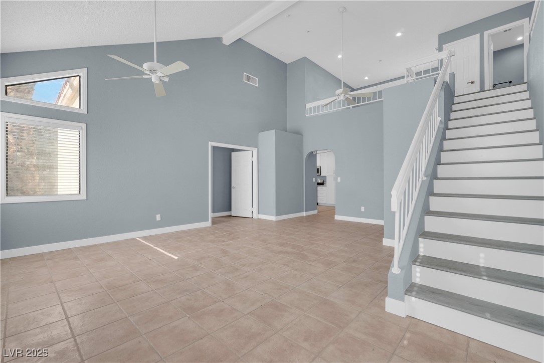 2716 Knightsbridge Road Henderson, NV 89074 - Photo 3 of 27 Unfurnished living room featuring a ceiling fan, beamed ceiling, high vaulted ceiling, arched walkways, and light tile patterned flooring