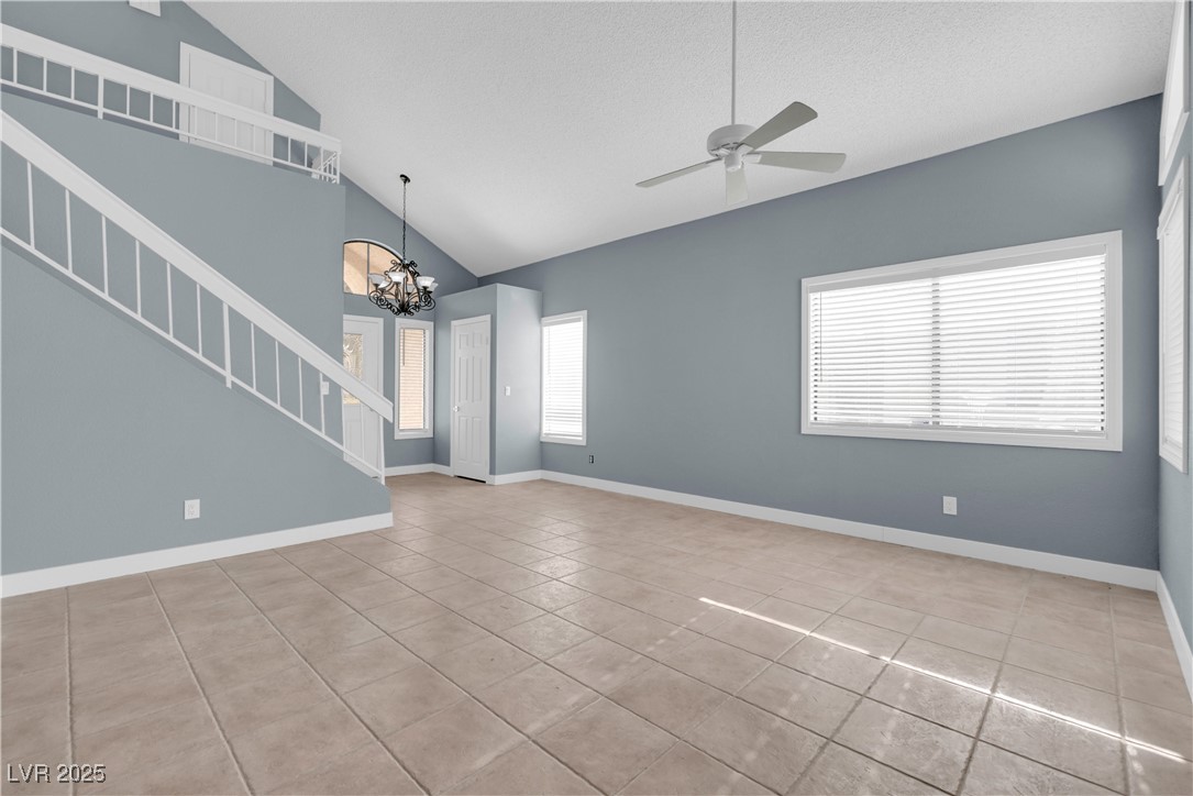 2716 Knightsbridge Road Henderson, NV 89074 - Photo 5 of 27 Unfurnished living room with stairway, a chandelier, light tile patterned floors, a ceiling fan, and high vaulted ceiling