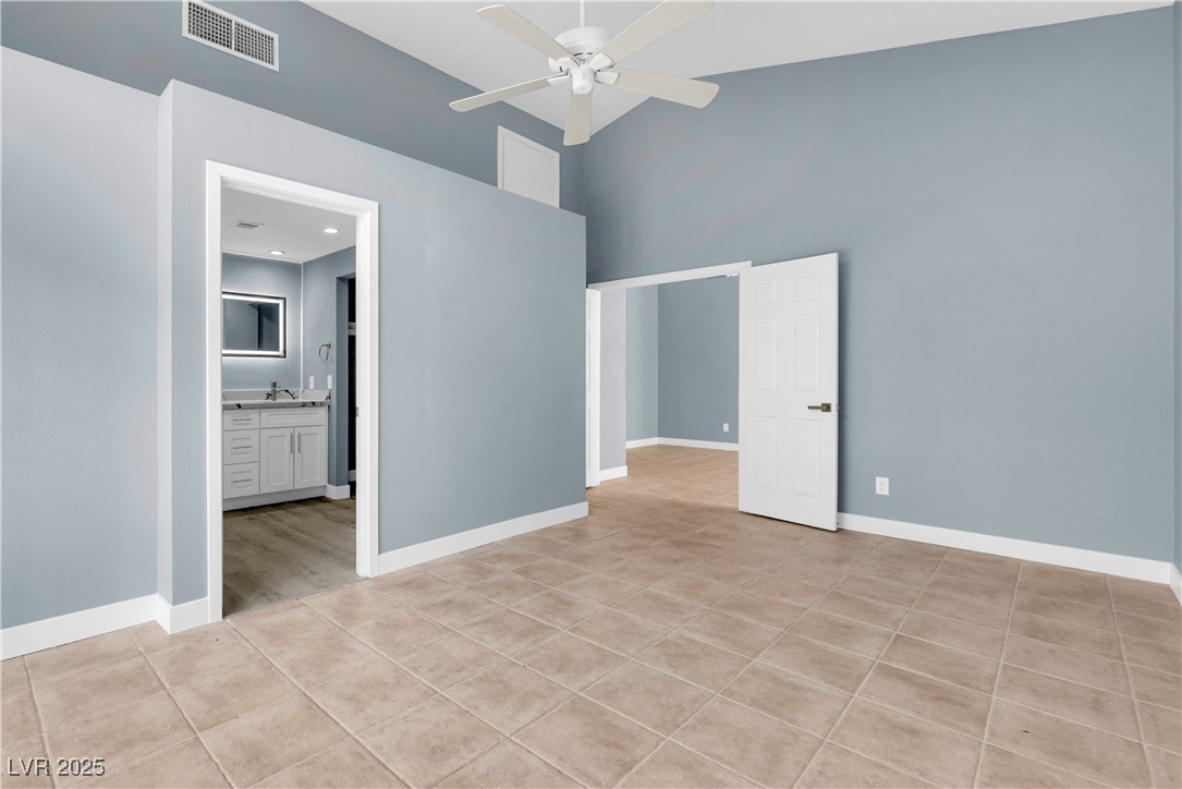 2716 Knightsbridge Road Henderson, NV 89074 - Photo 7 of 27 Unfurnished bedroom featuring light tile patterned flooring, high vaulted ceiling, ceiling fan, and connected bathroom