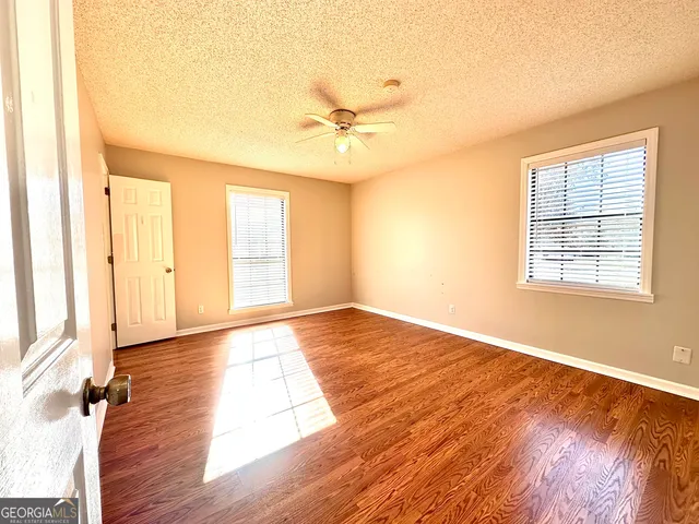 an empty room with wooden floor and windows