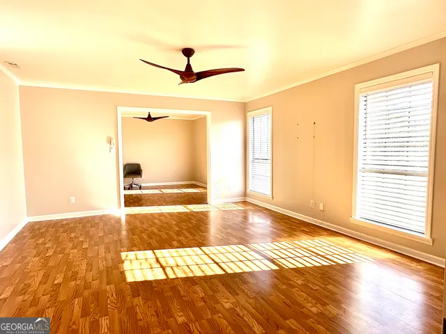 a view of an empty room with wooden floor and a window