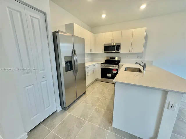 a kitchen with stainless steel appliances a refrigerator sink and microwave