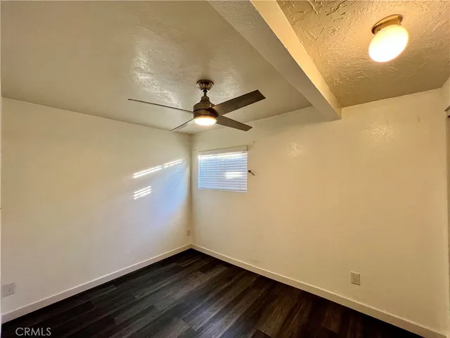 en empty room with wooden floor and fan
