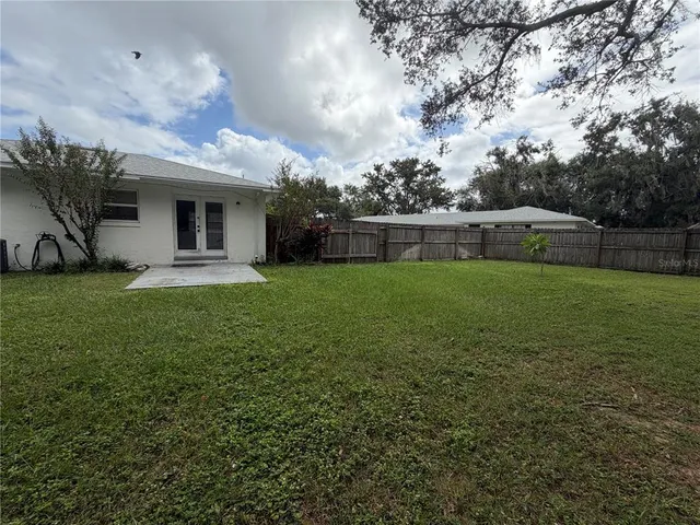 a view of a house with a yard and a large tree