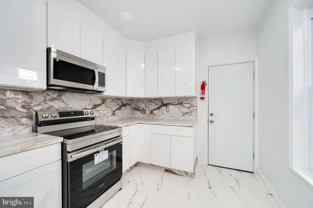 a kitchen with granite countertop white cabinets and stainless steel appliances