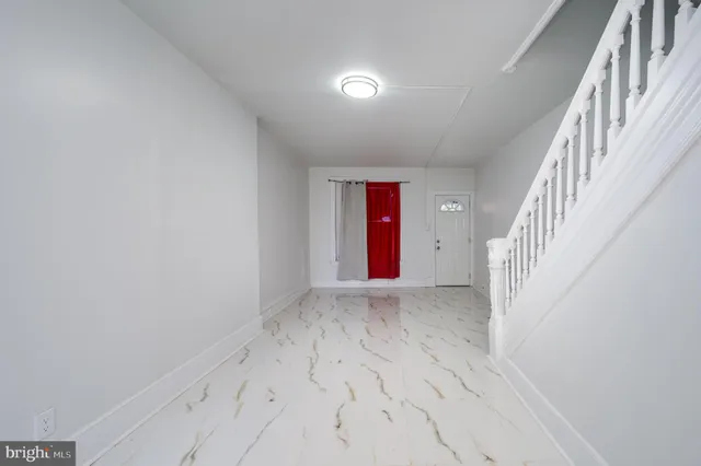 a view of an empty room with wooden floor and stairs