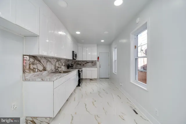 a large white kitchen with a refrigerator a stove a sink and a window