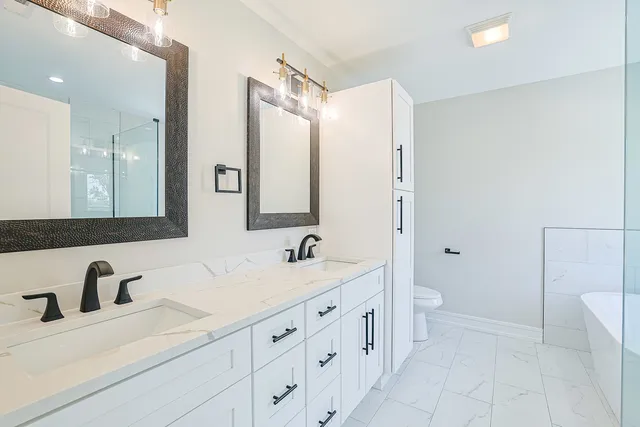 a bathroom with a double vanity sink mirror and toilet