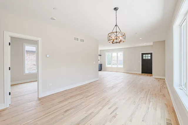 a view of an empty room with wooden floor and windows