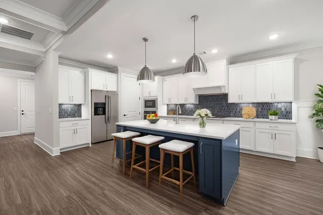 a kitchen with stainless steel appliances granite countertop a sink a stove a refrigerator and white cabinets with wooden floor