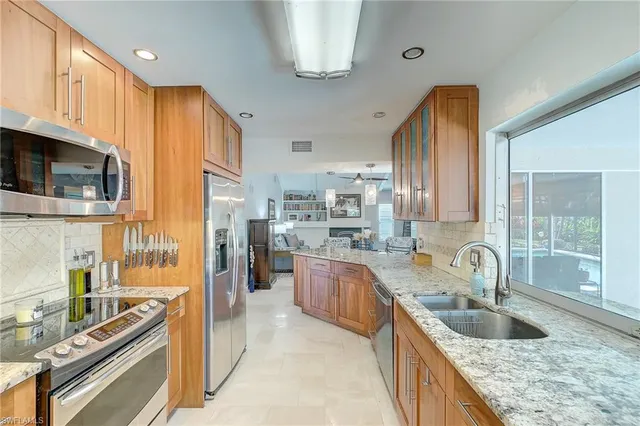 a kitchen with granite countertop a sink stainless steel appliances a counter top space and cabinets