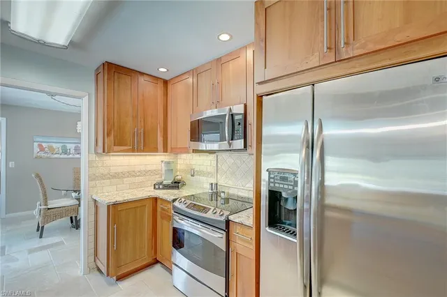 a kitchen with stainless steel appliances granite countertop a refrigerator a stove and a sink with wooden floor