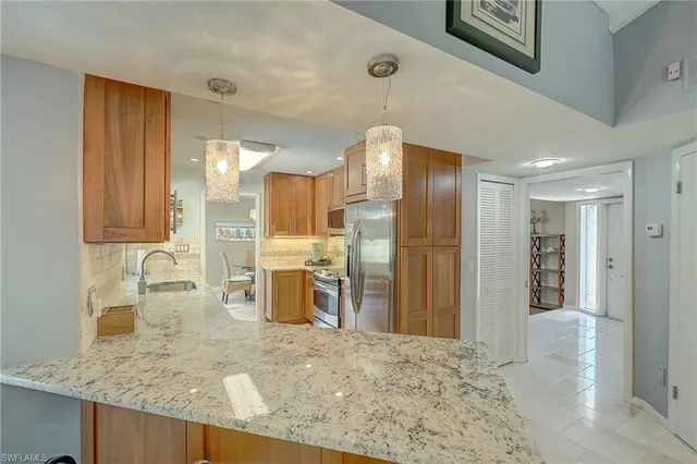 a view of a kitchen with kitchen island granite countertop a refrigerator and cabinets