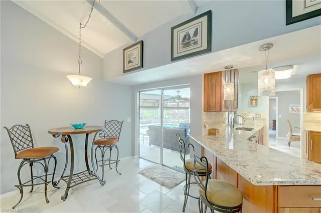 a view of a dining room and livingroom with furniture wooden floor a rug a painting and a chandelier