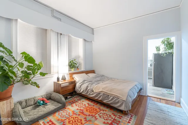 a bedroom with a bed potted plant with the wooden floor
