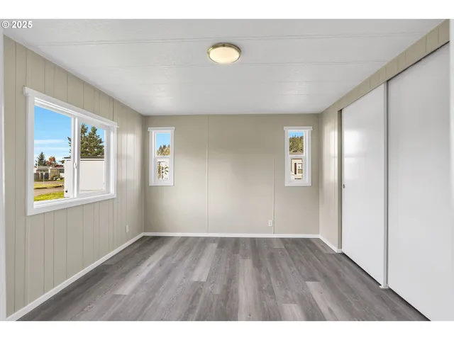 a view of an empty room with wooden floor and window