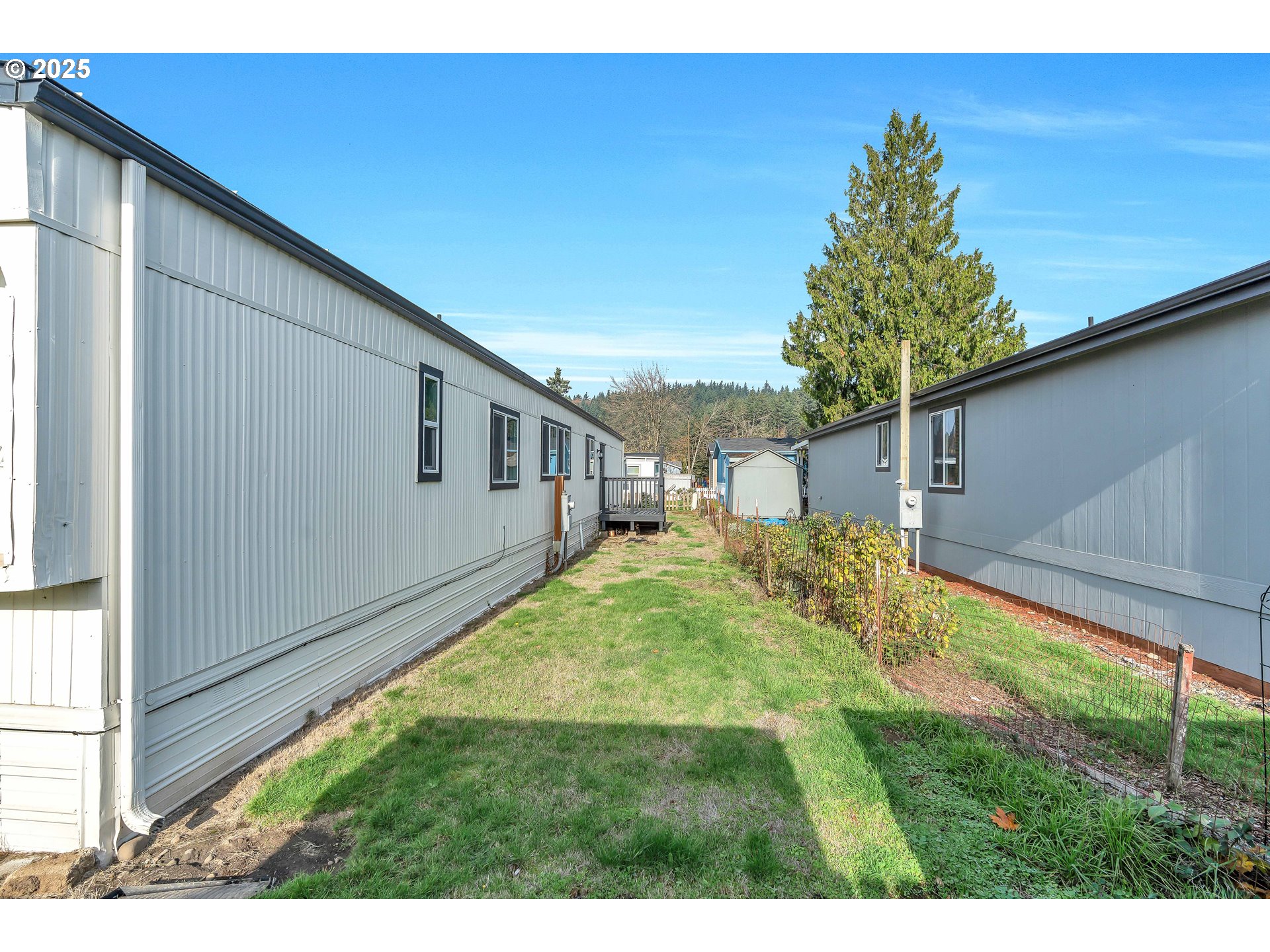 10701 Southeast Highway 212, Unit J3 Clackamas, OR 97015 - Photo 27 of 42 a backyard of a house with large trees and wooden fence