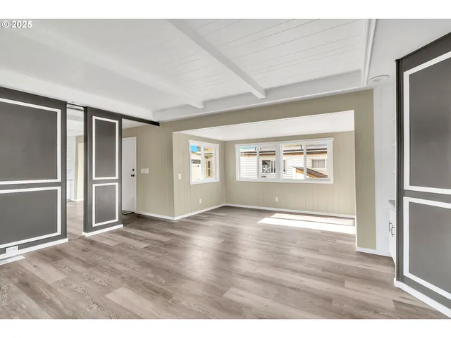 a view of an empty room with window and wooden floor
