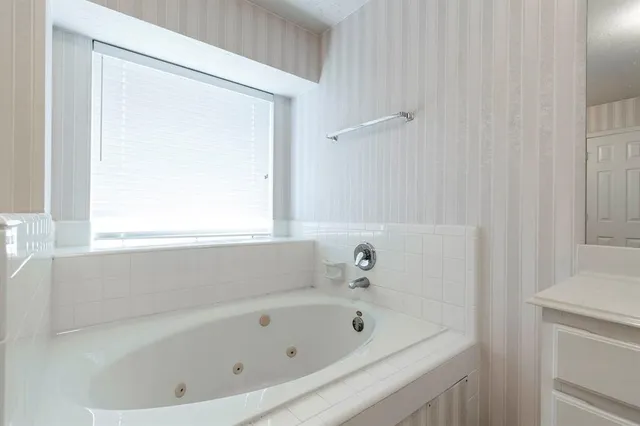 a white bath tub sitting next to a white sink and a vanity
