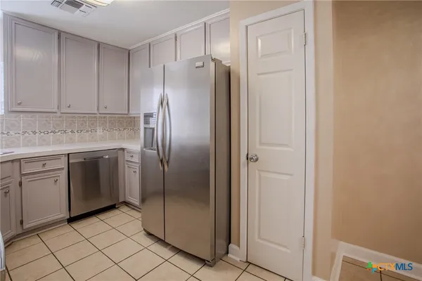 a kitchen with stainless steel appliances granite countertop a refrigerator and white cabinets